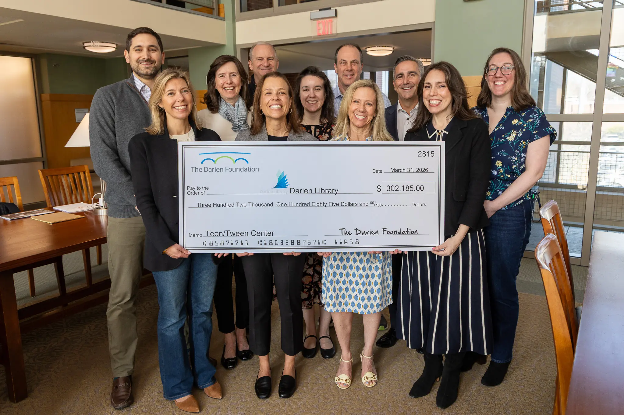 Members of The Darien Foundation and Darien Library stand together holding a physically large check. Pictured left to right: Richard Summers, Stefanie Desai, Sarah Woodberry, David Wren, Alex Eising, Elisabeth Marrocolla, Ward Glassmeyer, Angela Riley, Hutch Pegler, Kiera Parrott, Mia Orobona